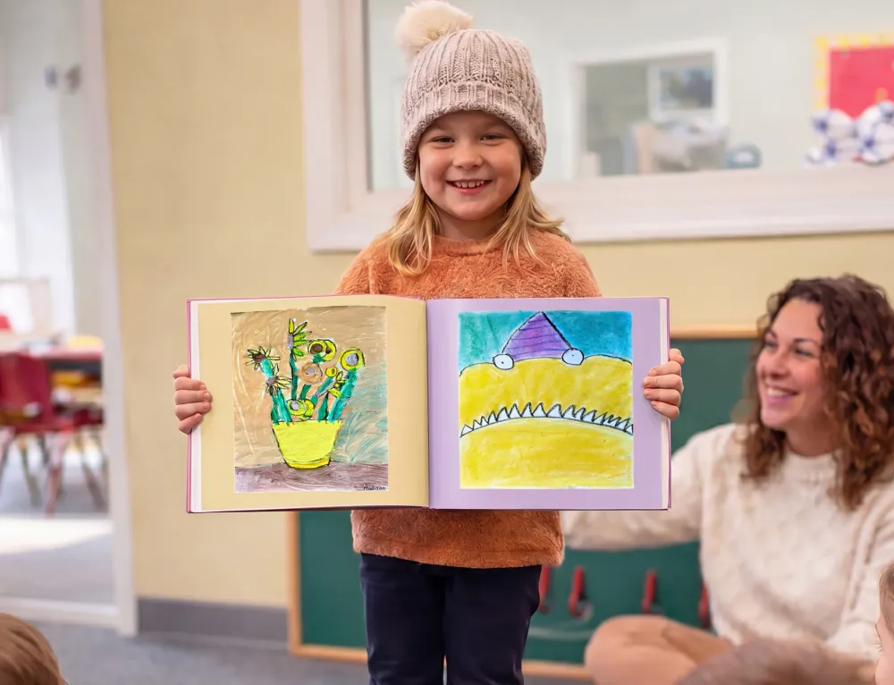 A proud elementary school student doing show-and-tell with their Scribble Art book