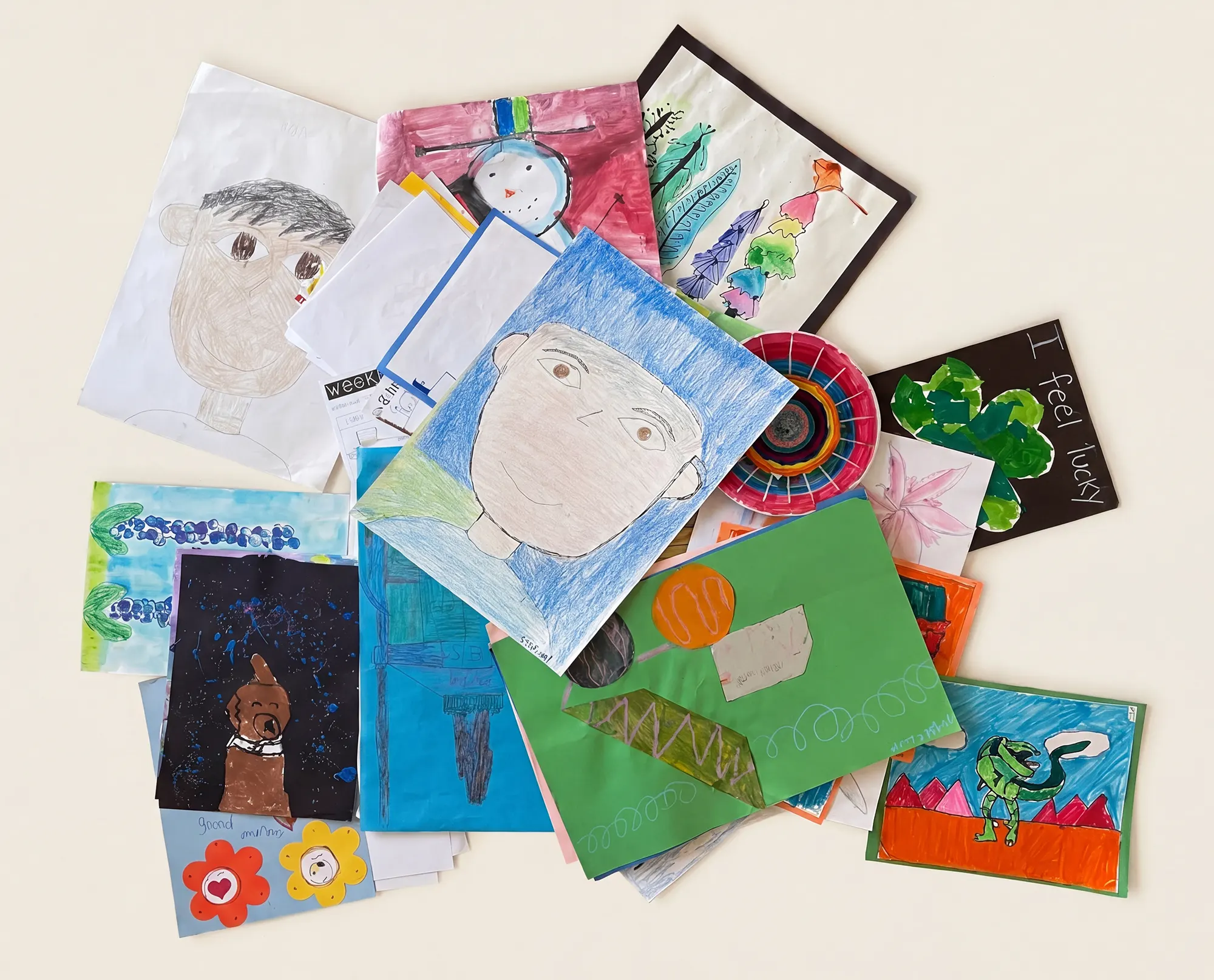 A pile of children's school artwork including drawings, paintings, and crafts