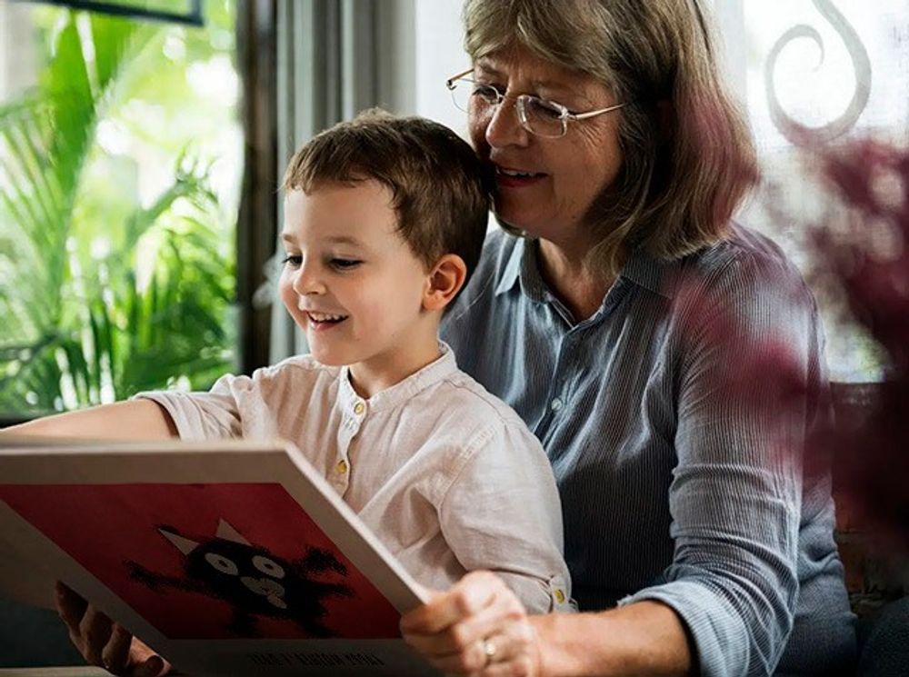 A cheerful grandmother with her proud grandson looking at their Scribble kids art photo book
