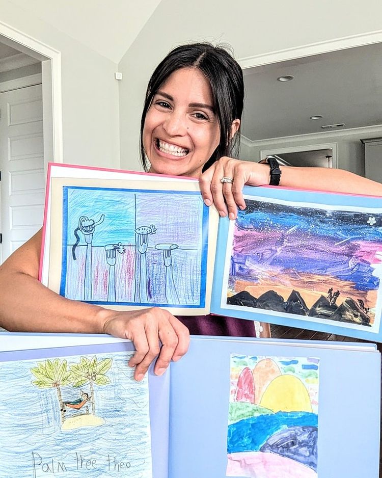 A woman proudly holding up two Scribble Art books.